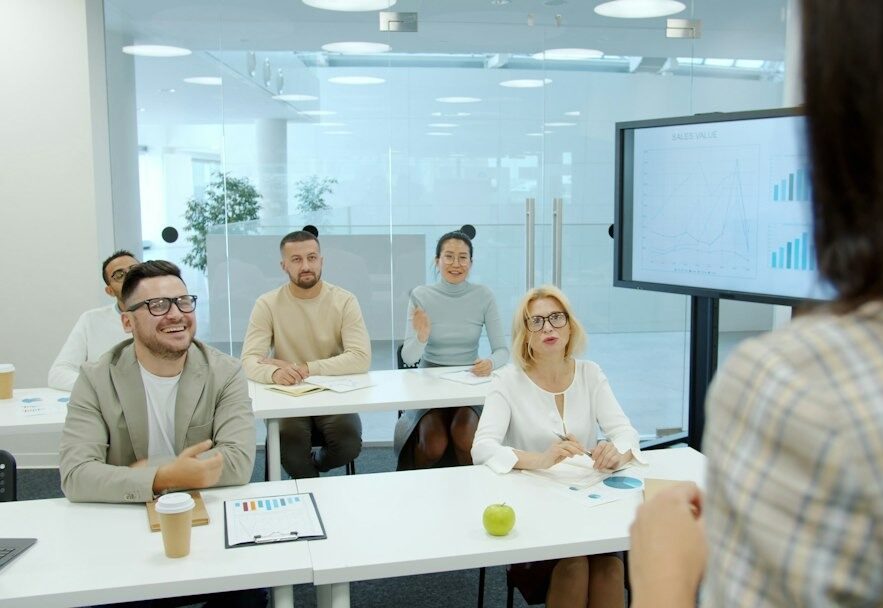 Business professional presenting to diverse attendees in a modern conference room.